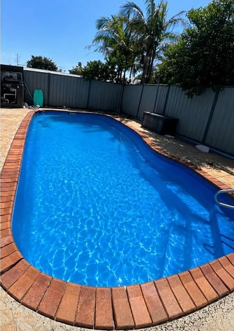 The same brick-edged pool with bright blue water after cleaning